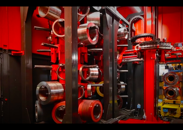 Close-up of the internal rollers and machined steel components inside a red industrial forming machine.